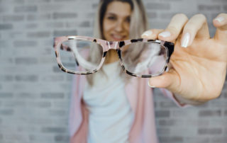 image of woman holding eye glasses