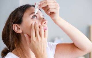 Young woman putting eye drops at home