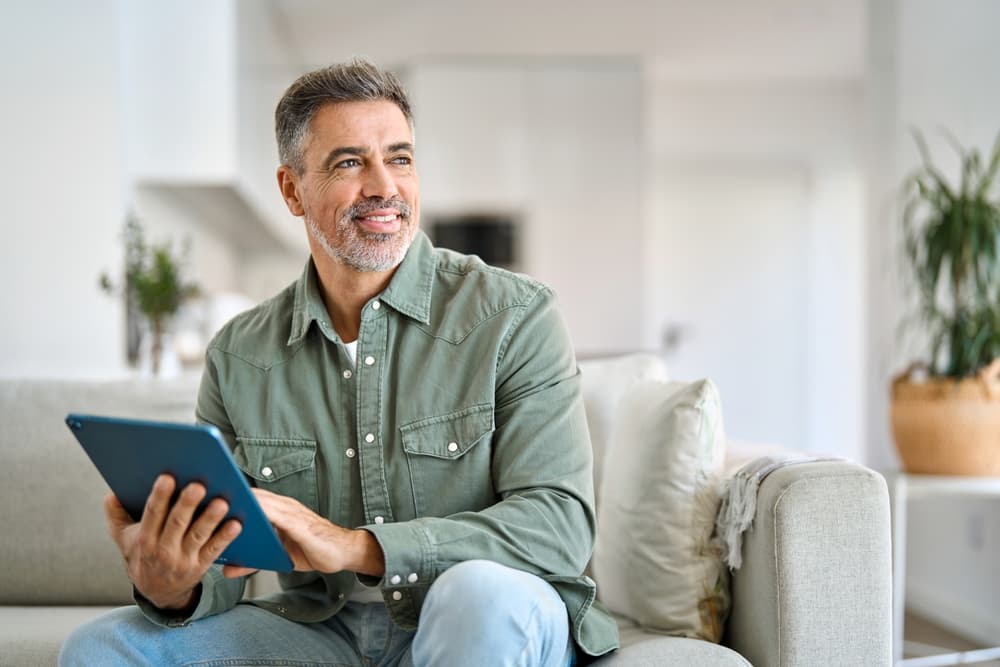 middle-aged-man-happy-reading-on-his-tablet-without-glasses